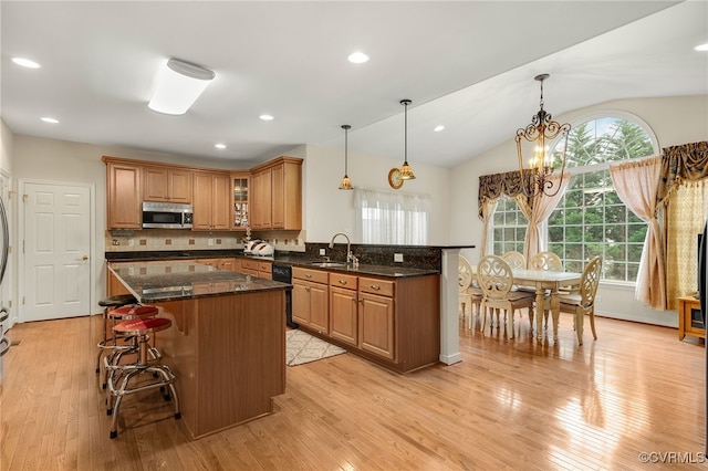 kitchen with a kitchen breakfast bar, light hardwood / wood-style flooring, and dark stone countertops