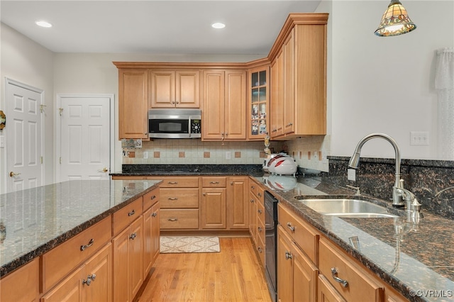 kitchen with sink, light hardwood / wood-style flooring, dishwasher, decorative light fixtures, and dark stone counters