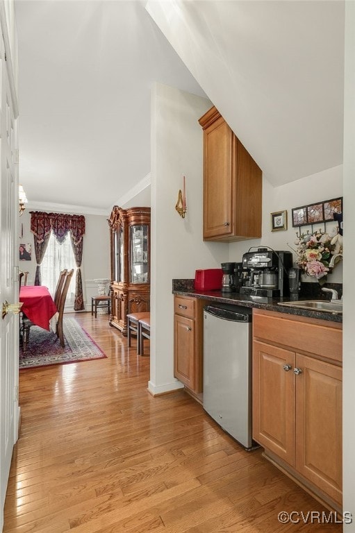 kitchen with vaulted ceiling, stainless steel dishwasher, light hardwood / wood-style floors, and sink