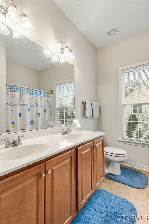 bathroom featuring vanity, toilet, tile patterned flooring, and a wealth of natural light