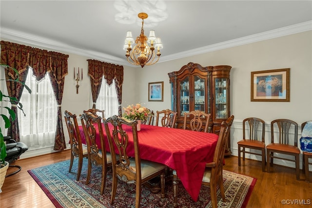 dining space with wood-type flooring, ornamental molding, and a chandelier