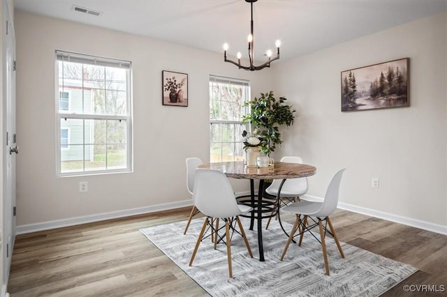 dining space featuring wood-type flooring and a notable chandelier