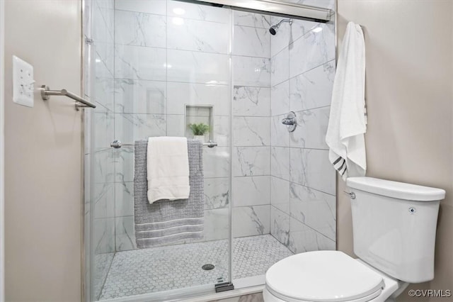 bathroom with a shower with shower door and toilet