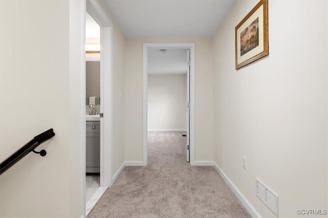 corridor with sink and light carpet