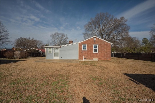 back of house featuring a carport and a lawn