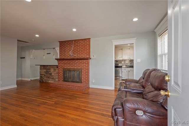 living room featuring hardwood / wood-style flooring and a brick fireplace