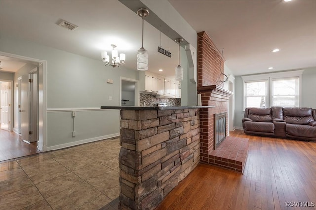 interior space with an inviting chandelier, a fireplace, and dark hardwood / wood-style flooring