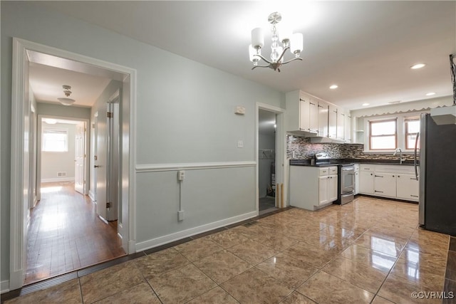 kitchen with tasteful backsplash, stainless steel appliances, decorative light fixtures, and white cabinets