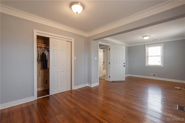 unfurnished bedroom featuring crown molding, dark wood-type flooring, and a closet