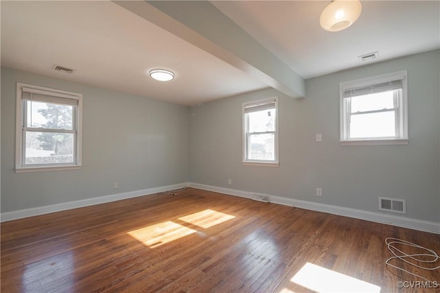 empty room with dark wood-type flooring and beam ceiling