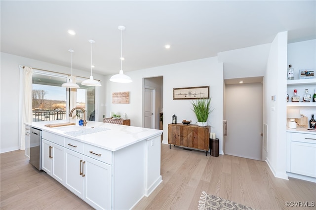 kitchen with decorative light fixtures, sink, white cabinets, stainless steel dishwasher, and light hardwood / wood-style flooring