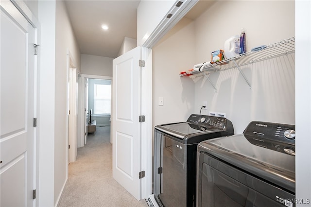 clothes washing area with light carpet and washer and clothes dryer