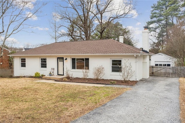 single story home featuring an outbuilding, a garage, and a front lawn