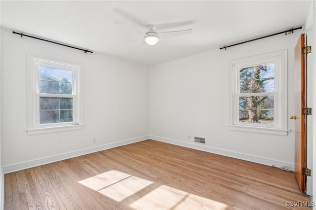 empty room with ceiling fan, plenty of natural light, and light wood-type flooring