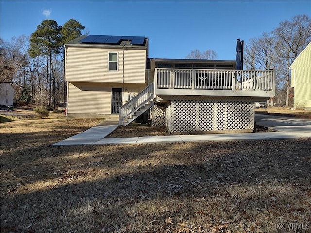 rear view of property featuring a wooden deck and solar panels