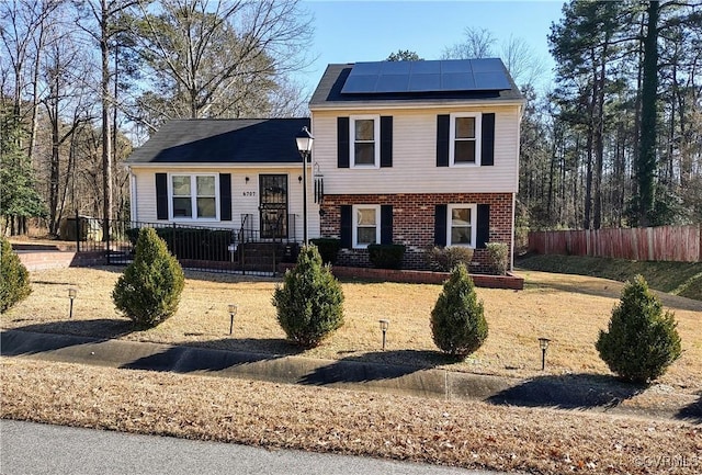 split level home with a front yard and solar panels