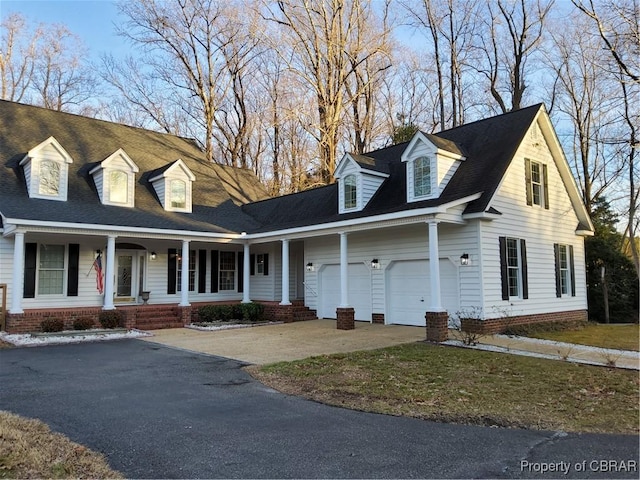 cape cod home featuring a garage and covered porch