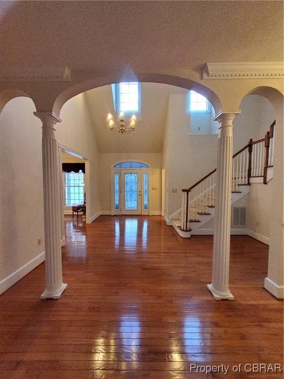 entrance foyer with ornate columns, dark hardwood / wood-style floors, a textured ceiling, and a chandelier