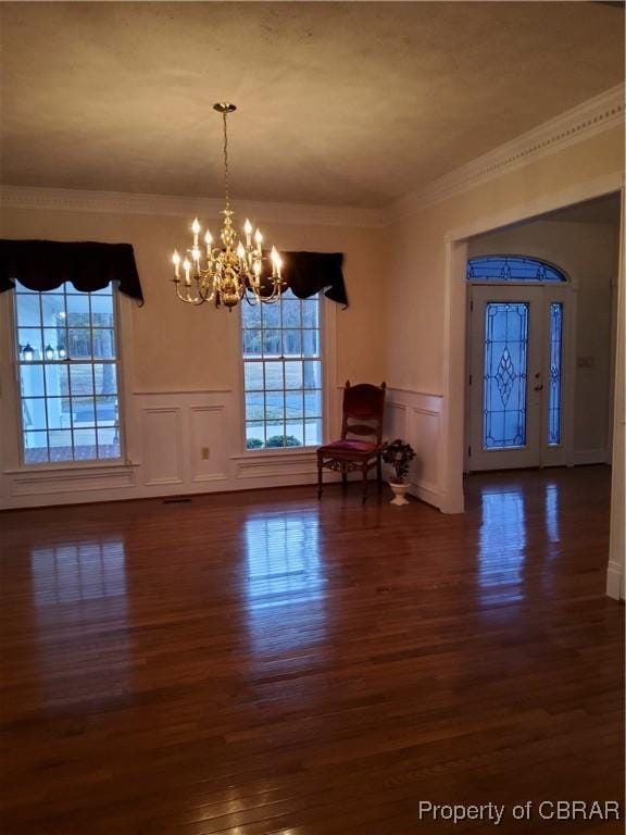 entrance foyer with crown molding, dark wood-type flooring, and an inviting chandelier