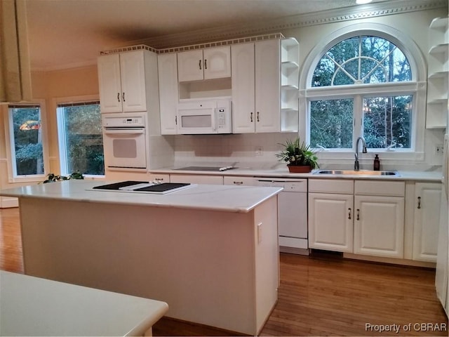 kitchen featuring sink, white cabinets, a center island, light hardwood / wood-style floors, and white appliances