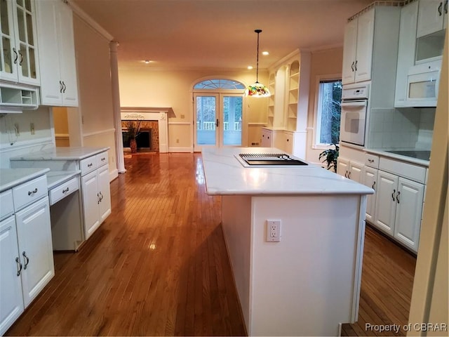 kitchen featuring white appliances, a center island, light hardwood / wood-style floors, white cabinets, and decorative light fixtures