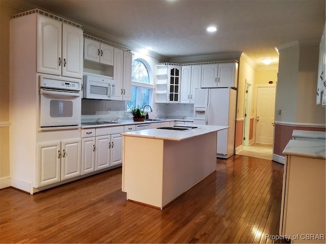 kitchen with sink, crown molding, white appliances, hardwood / wood-style flooring, and a kitchen island