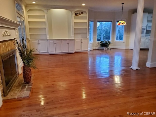 unfurnished living room featuring crown molding, hardwood / wood-style floors, and built in shelves