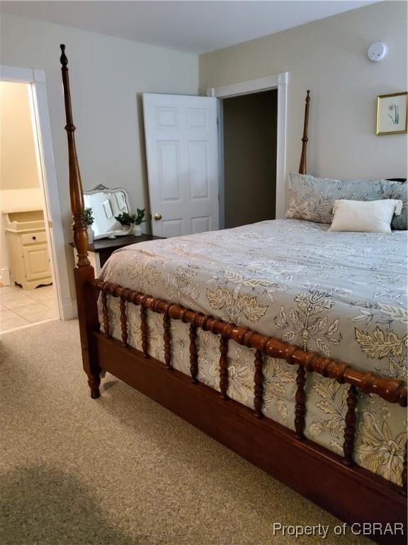 bedroom with ensuite bathroom and light carpet