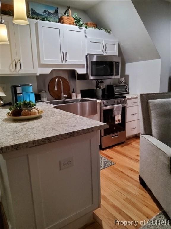 kitchen featuring white cabinetry, hanging light fixtures, light hardwood / wood-style flooring, and stainless steel appliances