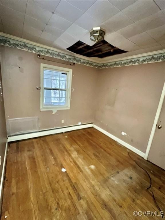 unfurnished room with baseboard heating, crown molding, and hardwood / wood-style flooring