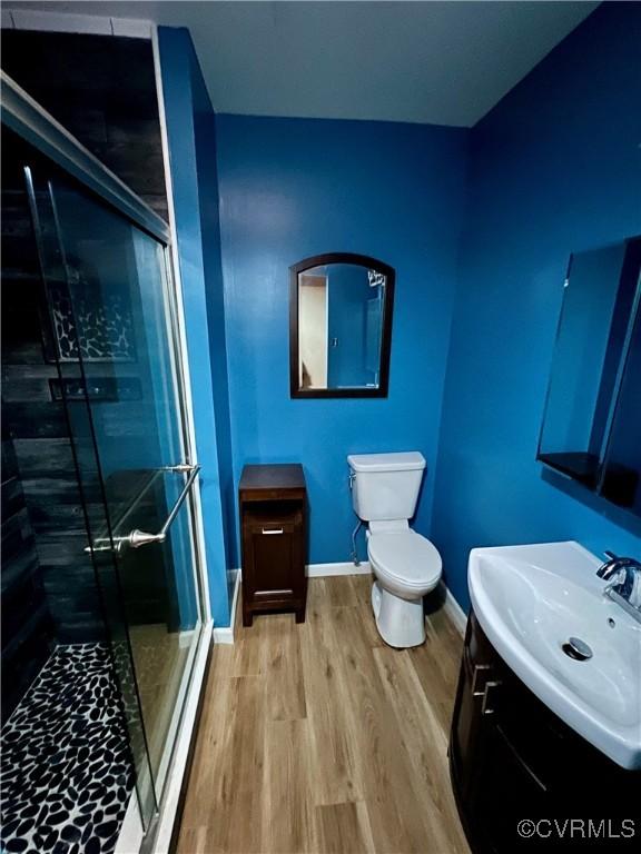 bathroom featuring vanity, an enclosed shower, hardwood / wood-style flooring, and toilet