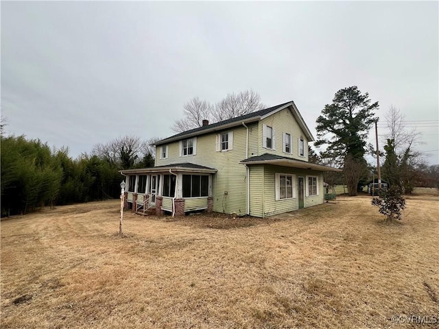 back of property with a sunroom and a yard