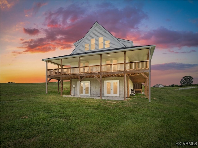 back house at dusk featuring a wooden deck and a lawn