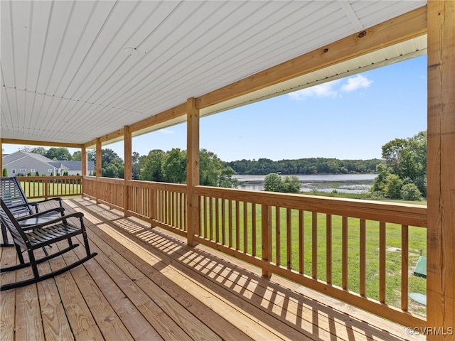 wooden terrace featuring a water view and a yard