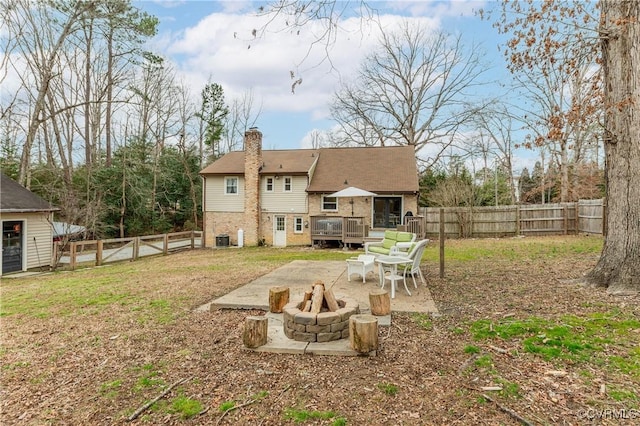 rear view of property featuring cooling unit, a wooden deck, a fire pit, and a patio