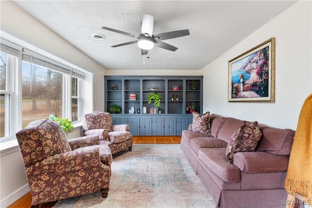 living room featuring ceiling fan, wood-type flooring, and a textured ceiling