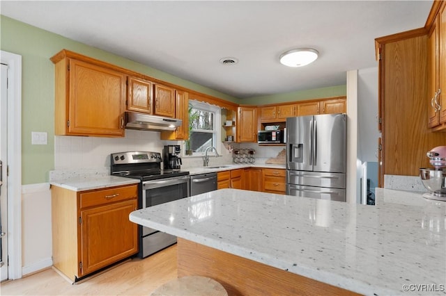 kitchen featuring light stone counters, appliances with stainless steel finishes, kitchen peninsula, and sink