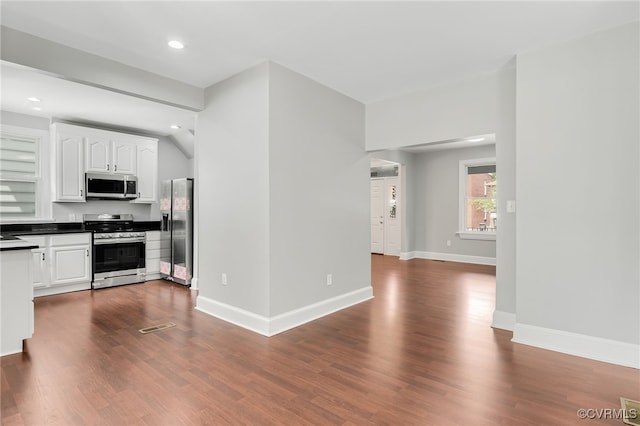 kitchen with dark hardwood / wood-style flooring, white cabinets, and appliances with stainless steel finishes