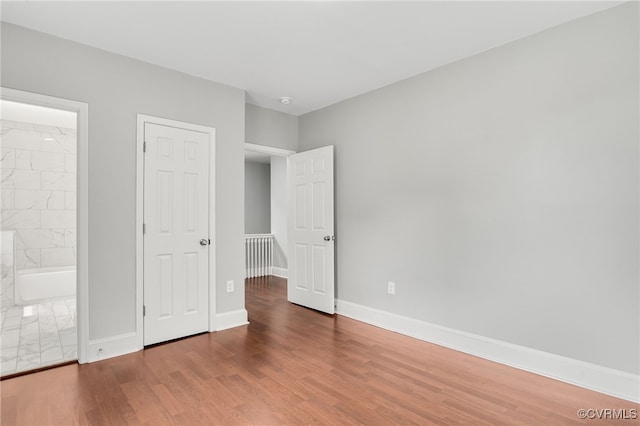 unfurnished bedroom featuring hardwood / wood-style floors and ensuite bathroom