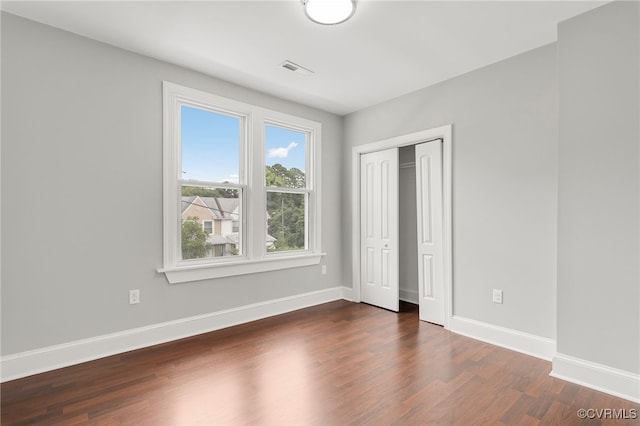 unfurnished bedroom featuring dark hardwood / wood-style floors and a closet