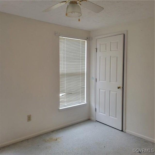 carpeted spare room featuring a textured ceiling and ceiling fan