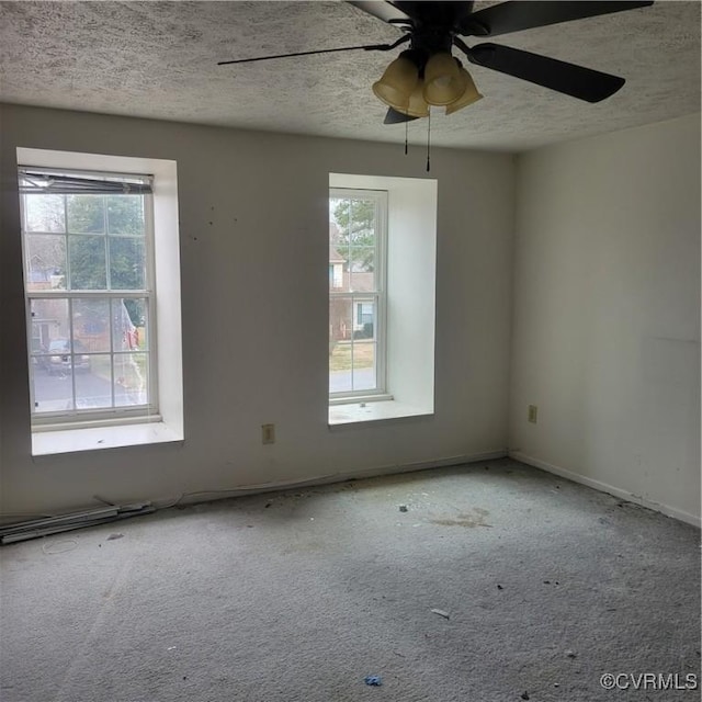 empty room featuring ceiling fan, carpet flooring, and a textured ceiling