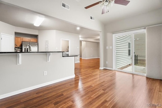 kitchen featuring lofted ceiling, a breakfast bar, light wood-type flooring, stainless steel fridge, and ceiling fan