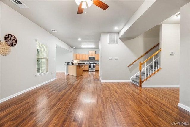 unfurnished living room featuring dark wood-type flooring, sink, and ceiling fan