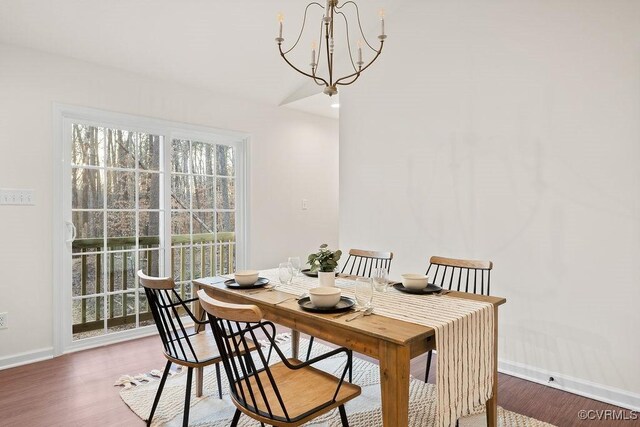 dining space with dark wood-type flooring and a notable chandelier