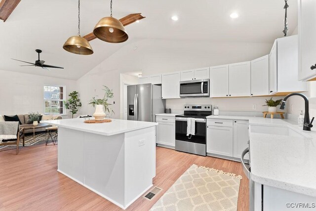 kitchen featuring pendant lighting, sink, appliances with stainless steel finishes, white cabinets, and light wood-type flooring