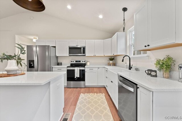 kitchen featuring sink, light stone counters, hanging light fixtures, stainless steel appliances, and white cabinets