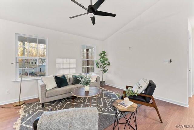 living room featuring a wealth of natural light, wood-type flooring, and vaulted ceiling