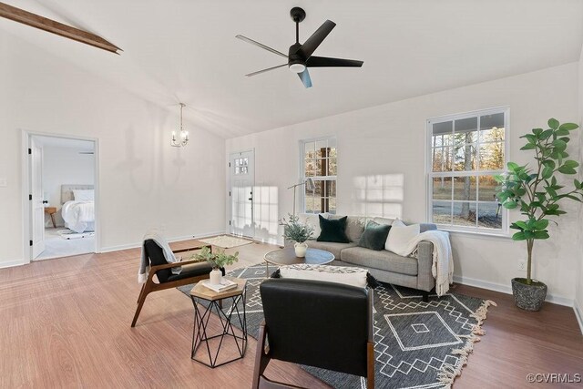 living room featuring vaulted ceiling, wood-type flooring, and ceiling fan with notable chandelier