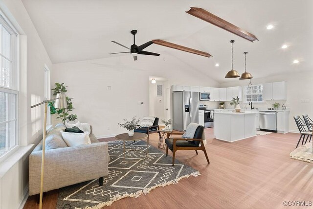 living room featuring ceiling fan, sink, high vaulted ceiling, and light hardwood / wood-style flooring